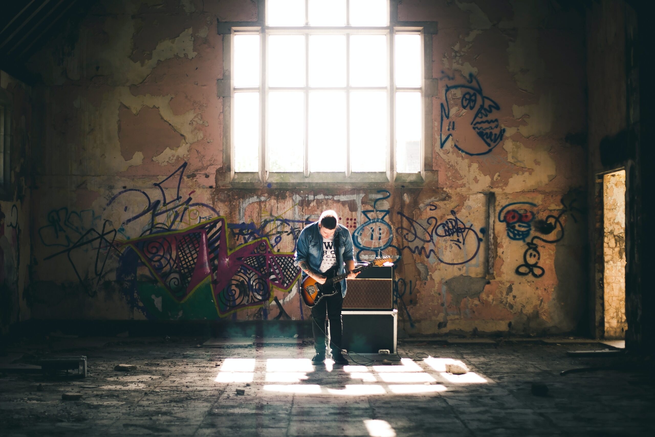 Young man practicing guitar in large wharehouse